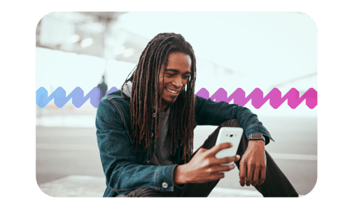 Man sitting and smiling while using his mobile device