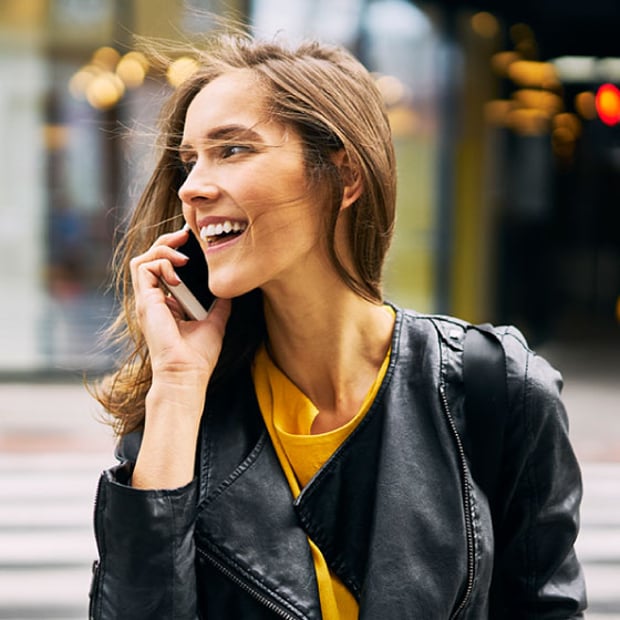Photo of a smiling woman outside on a windy day, talking on her cell phone