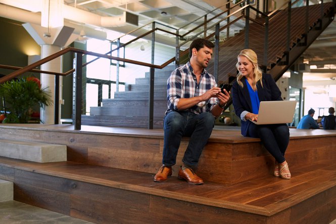 Colleagues using a smartphone and laptop.