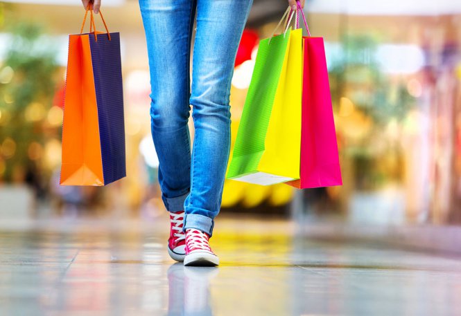 Woman walks in a mall with multicolored shopping bags.