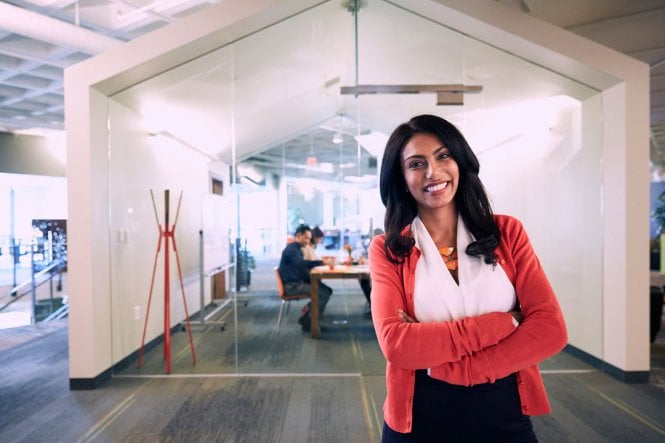 A smiling woman in a modern office space.
