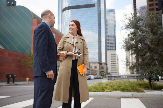 A man and woman talking outside in a city.
