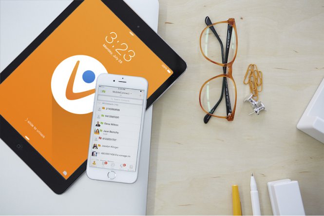 A smartphone and tablet on a desk, along with a pair of glasses and pens.