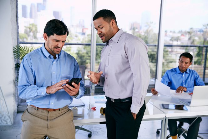 A man showing his smartphone to another man.