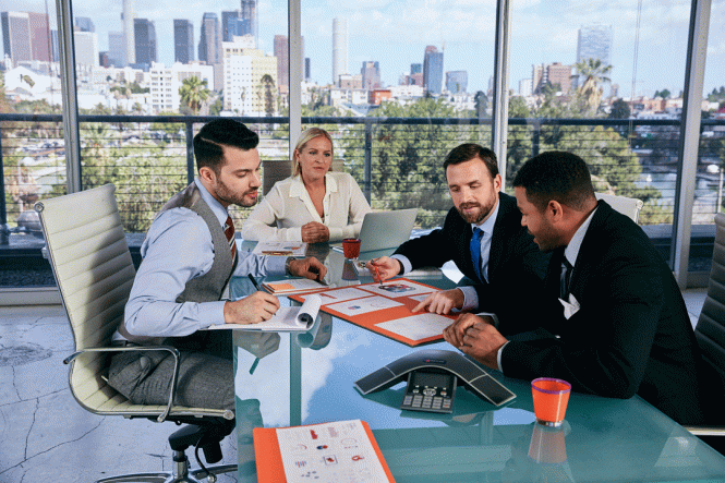 Three men and a woman sitting at a desk during a business meeting.
