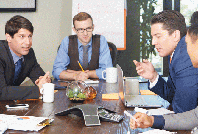 Four men sitting around a conference phone.
