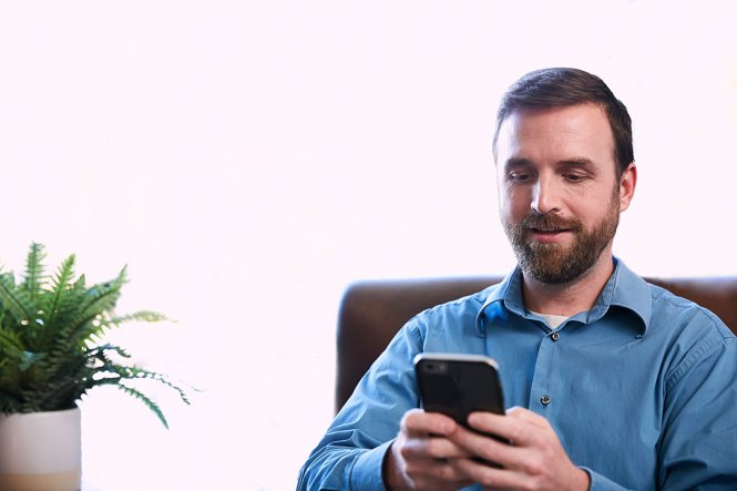 A man sitting at a desk, using a smartphone.