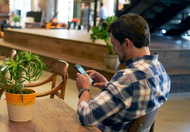 A man sitting at a table, using his smartphone.