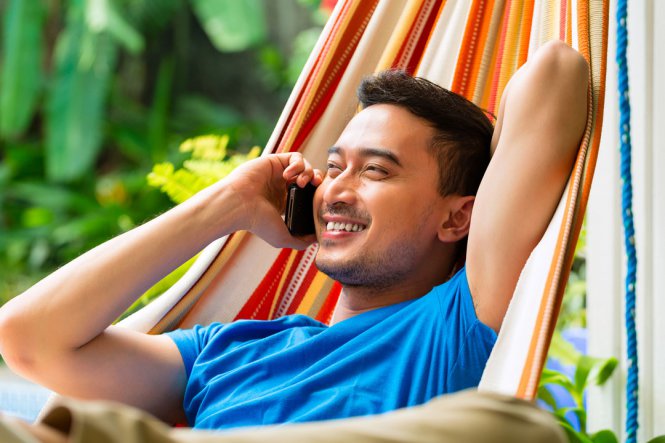 Man talks on the phone in a hammock.
