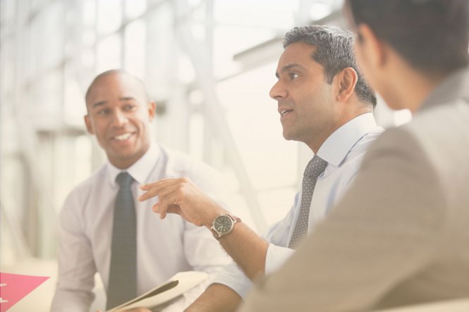 Three people having a discussion in an office.