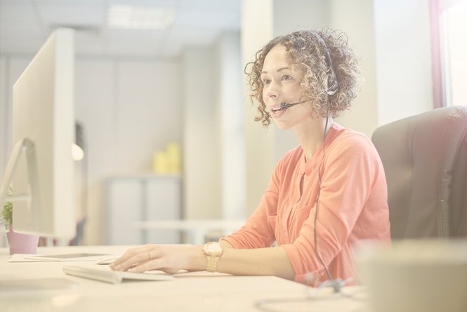 A woman speaking on the phone at her desk, using a headset.