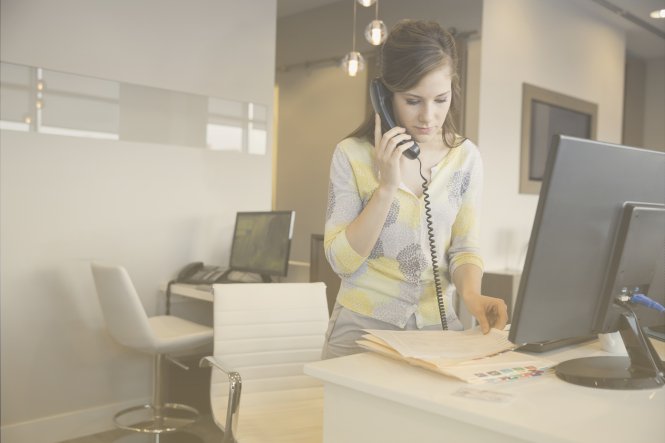 A woman using a telephone in an office.