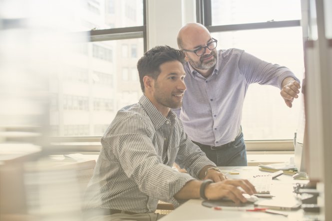 Two men in an office, collaborating and viewing a computer screen.
