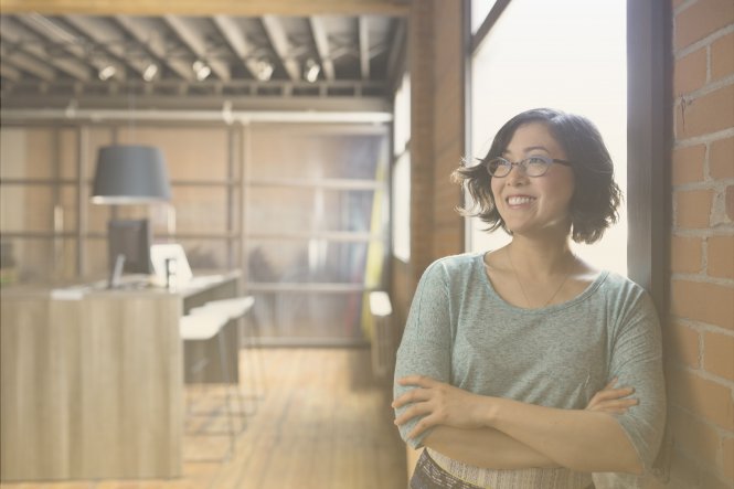 A woman standing in a modern office, smiling.