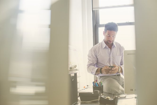 A man in an office, using a smartphone.