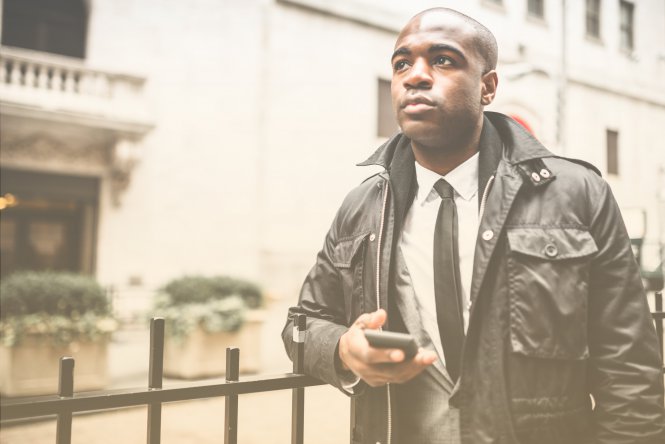 A man in a suit using a smartphone in the city.