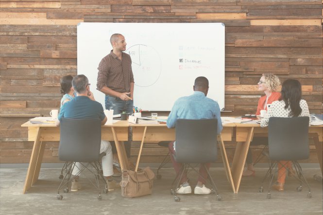 A small business leader making a presentation for his team, in front of a dry-erase board.