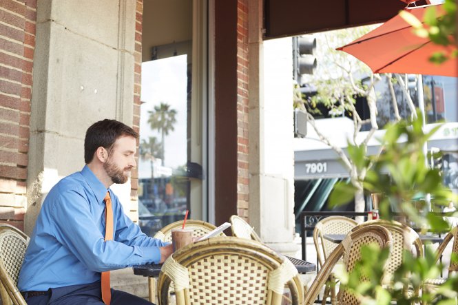 A man sitting at a restaurant using a tablet.