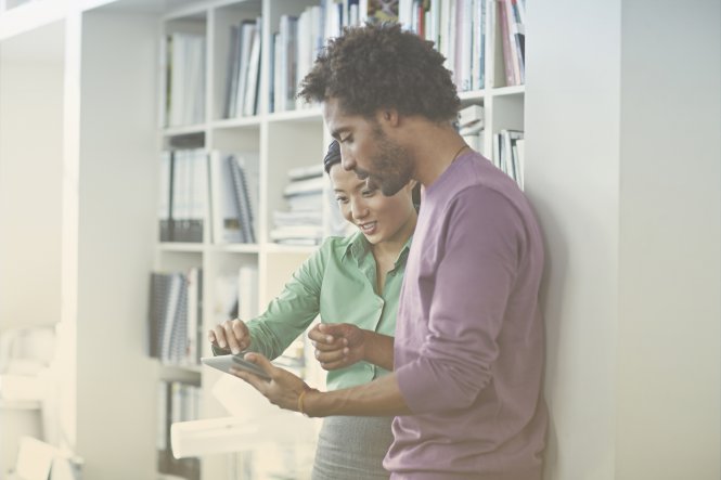A man and a woman implementing enterprise mobile device management practices on a tablet.