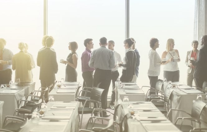 Colleagues standing together, talking during a conference.