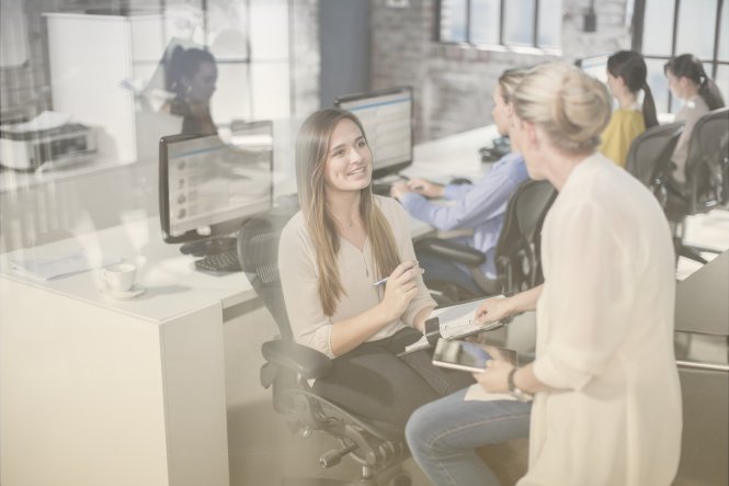 Two women enjoying agility in the workplace by having a chat in their open office.