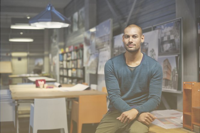 A man sitting on a desk in a modern office.