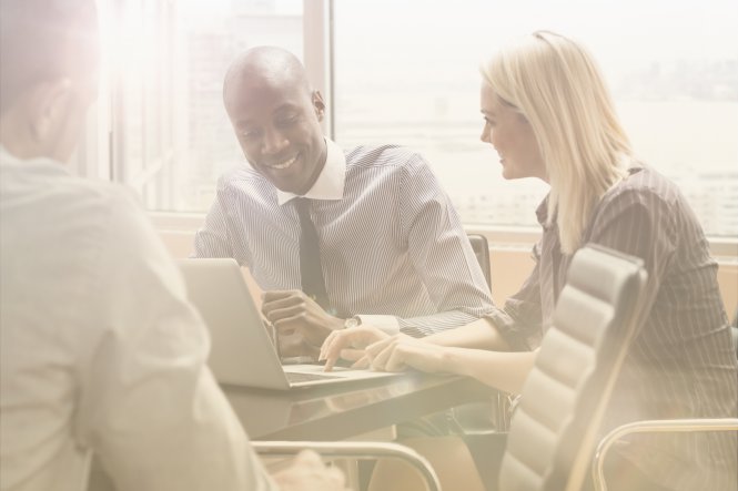 Employees, understanding cloud technology benefits, gather around a computer.