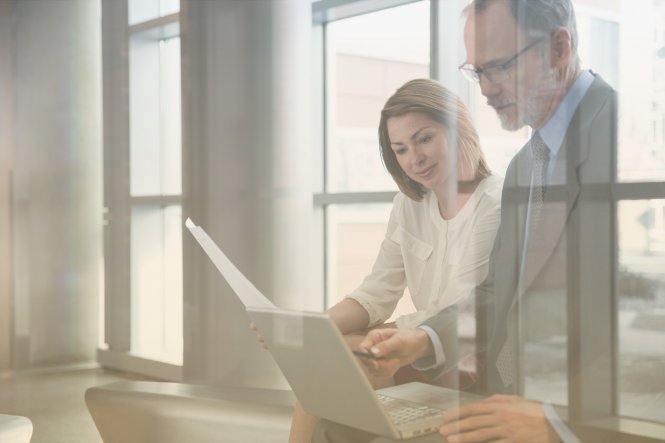 A woman and a man reviewing new automated business processes on a laptop.