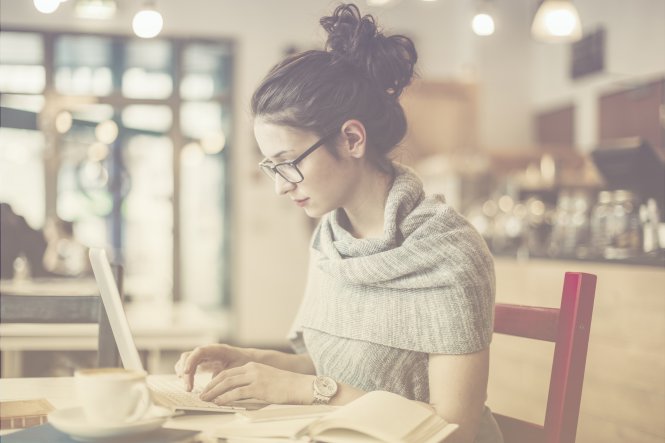 A woman using a laptop in a coffee shop.
