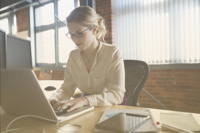 Woman typing on a laptop computer.