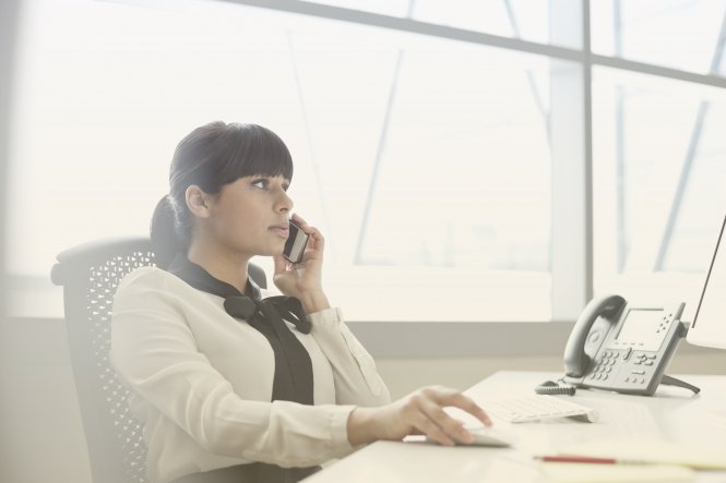 A woman using SD-WAN-as-a-service while using her smartphone in the office.