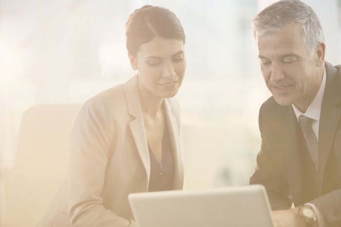 A man and a woman following an SD-WAN deployment guide on a laptop.
