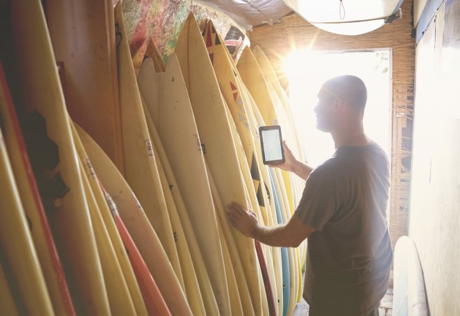 Retail store owner considers business phone options while looking at merchandise.