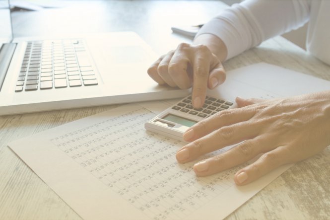 An accountant with a calculator using accountant productivity technology on their laptop