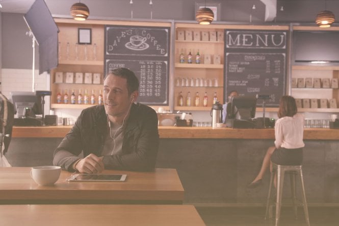 Man seated at a table in a cafe that employees a strong restaurant communication strategy.