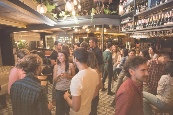 A crowd of patrons waits for tables in a restaurant that uses SMS restaurant communications