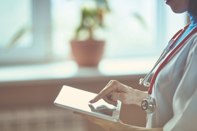 A physician accesses urgent care communication technology on her tablet