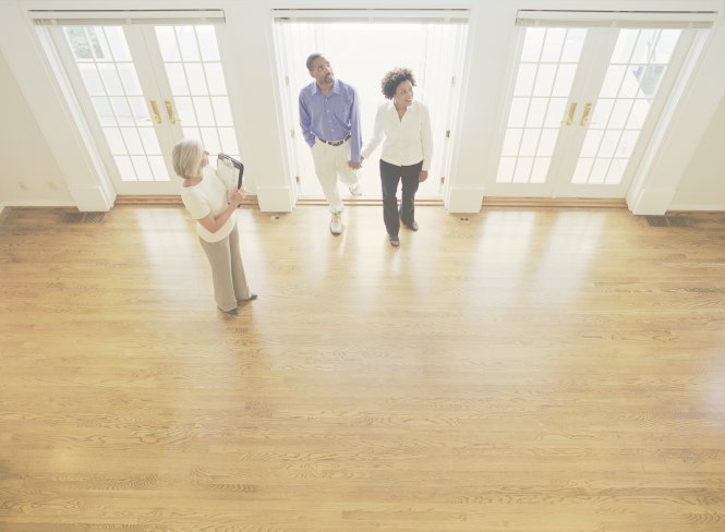 An agent with quality real estate leads shows an enthusiastic couple a house