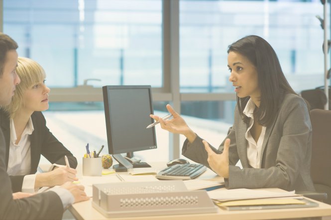 A credit union employee uses new communications solutions to assist two members with a loan