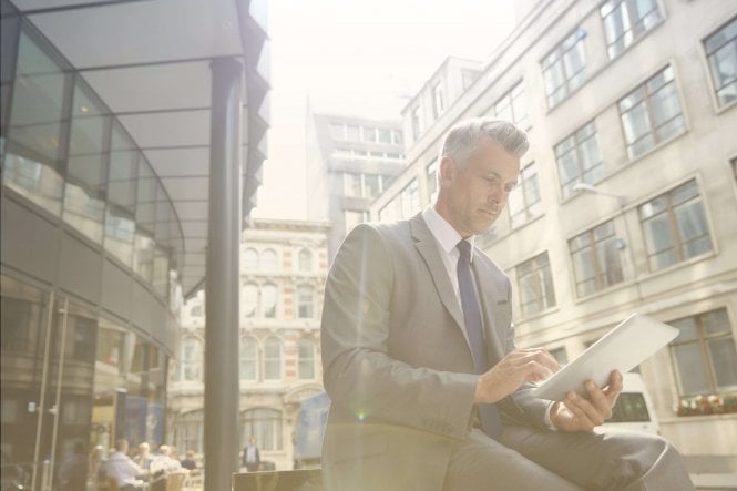 A suited man uses a tablet with an insurance agency BYOD policy.