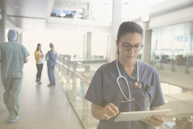 A healthcare employee using tech solutions that drive healthcare cost management on a tablet