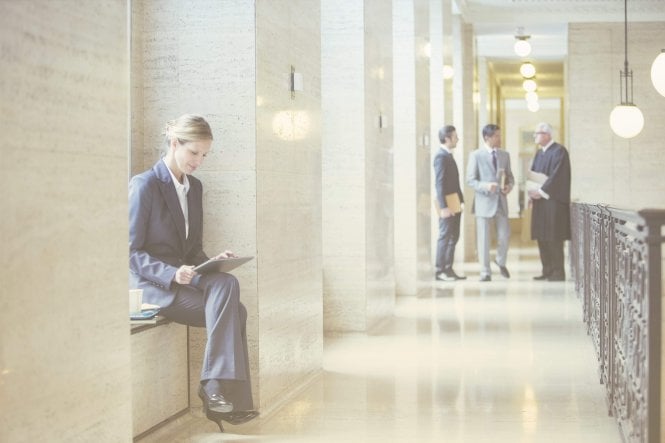 A lawyer beating law firm competition by communicating with clients on a tablet while in courthouse