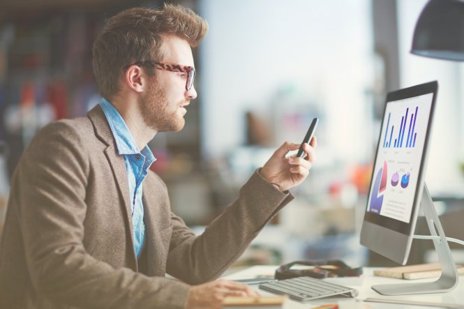 Financial planner looking at data on computer and mobile device