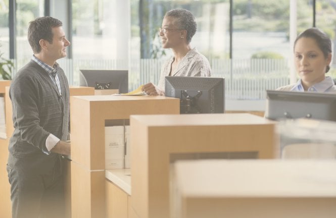Bank employee with skills for finance jobs serving a customer at the counter