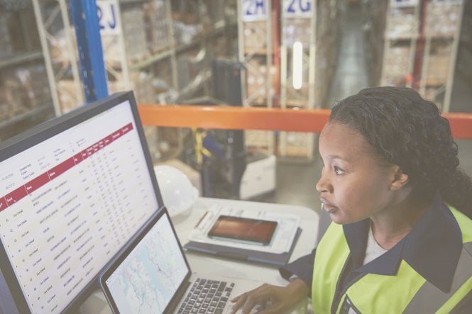 Employee in warehouse looking at data on screen representing manufacturing trends for 2019