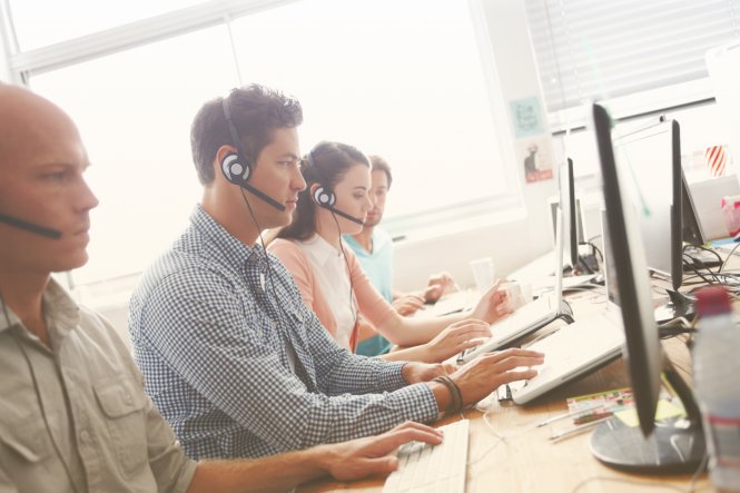 UCaaS and contact center agents with headsets taking customer calls at computer