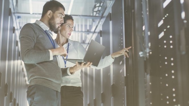 Two IT leaders looking at network servers and discussing biggest challenges for IT professionals