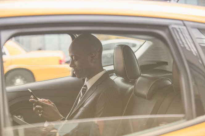 Businessperson in cab working on smartphone demonstrating mobile app use in business