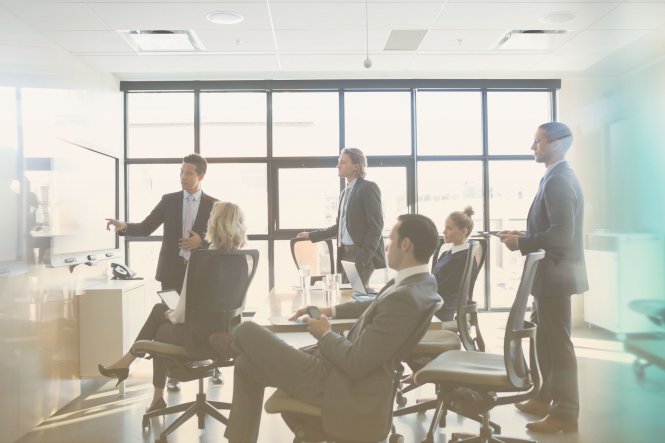 Group of businesspeople in suits looking at screen and discussing building client relationships