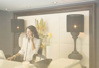 A woman talking on the phone at a reception desk, using SD-WAN solutions for quality of service.
